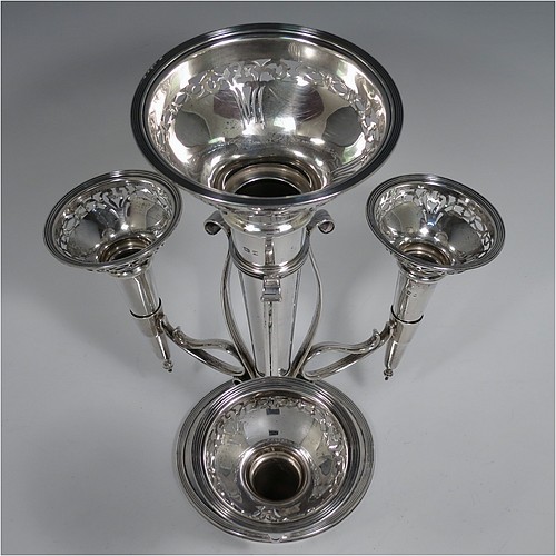A Sterling Silver flower vase epergne center-piece, having four removable flower vases with hand-pierced top borders, with a central larger vase and three smaller side vases, all sitting on a pedestal base with wire-work scroll holders and applied reed-edged borders. Made by Henry Matthews of Birmingham in 1922. The dimensions of this fine hand-made sterling silver flower epergne are height 28 cms (11 inches), spread across vases 24 cms (9.5 inches), and it weighs approx. 645g (21 troy ounces).