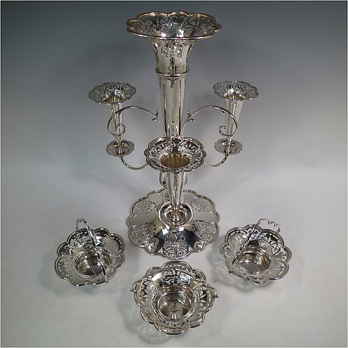 A very pretty Antique Edwardian Art Nouveau Sterling Silver table Epergne centrepiece, having a central large flower vase surrounded by three smaller vases and three removable swing-handled bowls, all with hand-pierced floral decoration, and sitting on a spreading lobed foot. Made by Fattorini and Sons of Birmingham in 1910/11. The dimensions of this fine hand-made antique silver Epergne table centrepiece are height 38.5 cms (15 inches), width 29 cms (11.5 inches), and it weighs a total of approx. 1,708g (55 troy ounces)