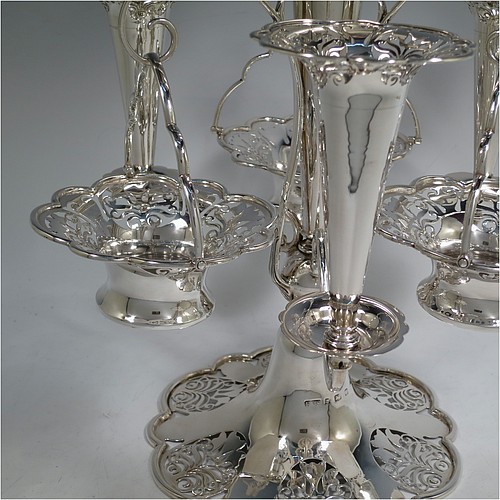 A very pretty Antique Edwardian Art Nouveau Sterling Silver table Epergne centrepiece, having a central large flower vase surrounded by three smaller vases and three removable swing-handled bowls, all with hand-pierced floral decoration, and sitting on a spreading lobed foot. Made by Fattorini and Sons of Birmingham in 1910/11. The dimensions of this fine hand-made antique silver Epergne table centrepiece are height 38.5 cms (15 inches), width 29 cms (11.5 inches), and it weighs a total of approx. 1,708g (55 troy ounces)