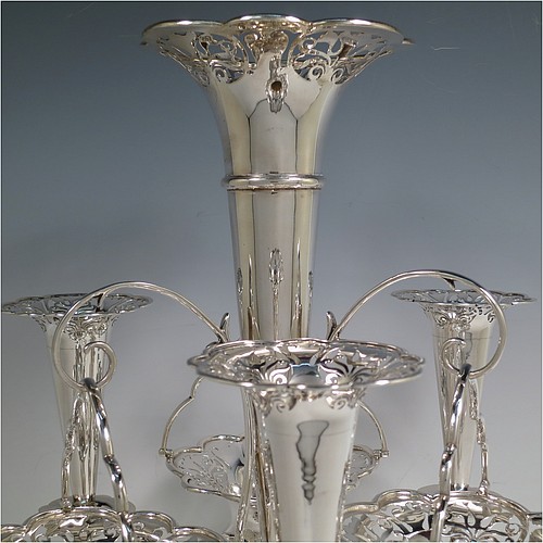 A very pretty Antique Edwardian Art Nouveau Sterling Silver table Epergne centrepiece, having a central large flower vase surrounded by three smaller vases and three removable swing-handled bowls, all with hand-pierced floral decoration, and sitting on a spreading lobed foot. Made by Fattorini and Sons of Birmingham in 1910/11. The dimensions of this fine hand-made antique silver Epergne table centrepiece are height 38.5 cms (15 inches), width 29 cms (11.5 inches), and it weighs a total of approx. 1,708g (55 troy ounces)