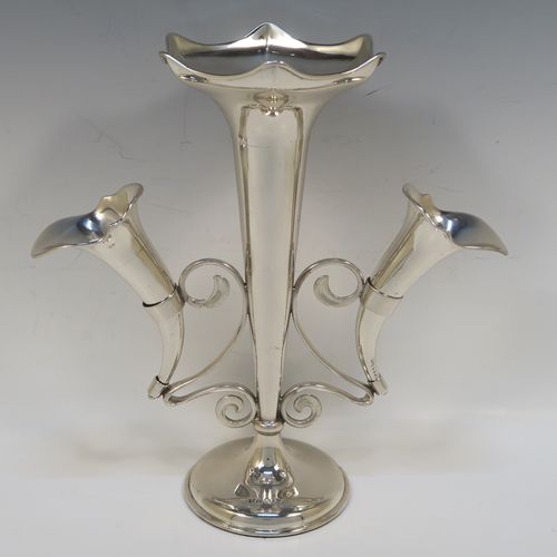 A pretty Antique Sterling Silver flower vase epergne center-piece in a plain round style, having two removable side flower vases connected to a central larger vase with scroll wire-work, and all sitting on a plain round pedestal base. This beautiful antique silver flower epergne was made by Joseph Gloster of Birmingham in 1913. The dimensions of this fine hand-made sterling silver flower centre-piece epergne are height 26 cms (10.25 inches), spread across vases 25.5 cms (10 inches), and it weighs approx. 465g (15 troy ounces).   