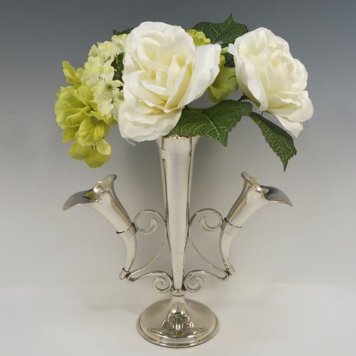 A pretty Antique Sterling Silver flower vase epergne center-piece in a plain round style, having two removable side flower vases connected to a central larger vase with scroll wire-work, and all sitting on a plain round pedestal base. This beautiful antique silver flower epergne was made by Joseph Gloster of Birmingham in 1913. The dimensions of this fine hand-made sterling silver flower centre-piece epergne are height 26 cms (10.25 inches), spread across vases 25.5 cms (10 inches), and it weighs approx. 465g (15 troy ounces).