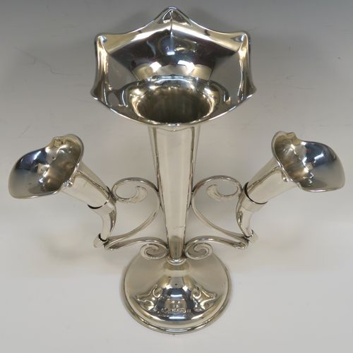 A pretty Antique Sterling Silver flower vase epergne center-piece in a plain round style, having two removable side flower vases connected to a central larger vase with scroll wire-work, and all sitting on a plain round pedestal base. This beautiful antique silver flower epergne was made by Joseph Gloster of Birmingham in 1913. The dimensions of this fine hand-made sterling silver flower centre-piece epergne are height 26 cms (10.25 inches), spread across vases 25.5 cms (10 inches), and it weighs approx. 465g (15 troy ounces).