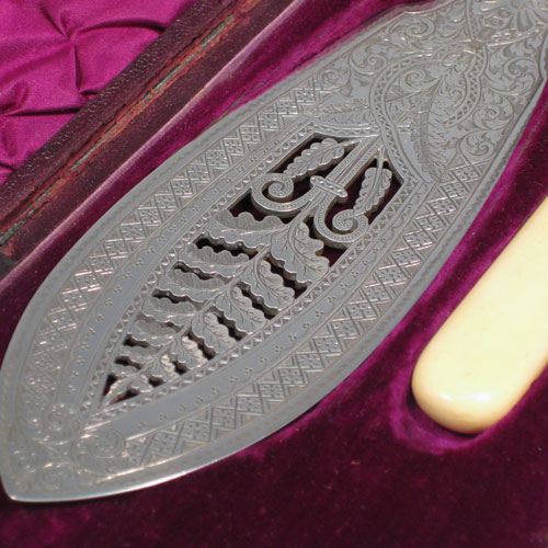    Antique Victorian sterling silver and bone-handled fish server set in original purple velvet and satin-lined presentation box, with hand-engraved floral decoration and hand-pierced blade and tines. Made by John Newman of Sheffield in 1882. Length of knife 32.5 (12.75 inches), length of fork 24 cms (9.5 inches).