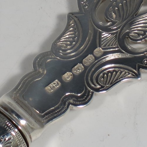An Antique Victorian sterling silver and ivory-handled fish server slice, having a hand-cut ivory handle with leaf decoration, a hand-pierced symmetrical blade with floral decoration and an engraved scene of a fisherman on one side, together with a silver ferrule between the blade and handle. Made by George Unite of Birmingham in 1872. The length of this fine hand-made antique silver fish serving slice is 31 cms (12.25 inches).