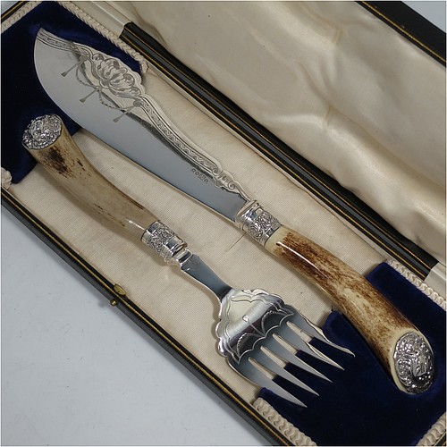 An Antique Edwardian Sterling Silver and Silver-Plated fish serving knife and fork set, having hand-carved antler bone handles that have hallmarked silver ferrules and end caps, with hand-engraved silver plated blade and tines with floral decoration, all in their original cream satin and dark blue velvet-lined presentation box. Made by Edward Smith of Sheffield in 1909. The dimensions of this fine hand-made antique silver and bone-handled fish serving set are length of knife 33 cms (13 inches), and length of fork 25 cms (9.75 inches).