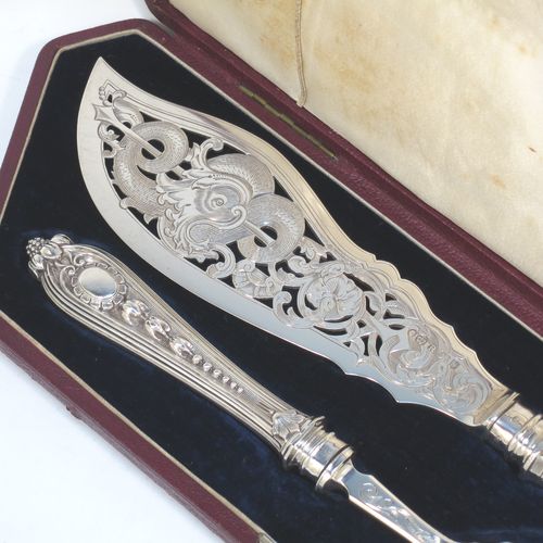 A very pretty Antique Victorian Sterling Silver pair of fish serving knife and fork set, having handles in a double-struck floral pattern with reeded sides, and hand-pierced blade and tines with hand-engraved dolphins, scroll, and floral decoration, all in their original dark blue velvet and cream satin lined presentation box. Made by Martin Hall and Co., of Sheffield in 1859. The dimensions of this fine hand-made antique silver fish serving set are length of knife 33 cms (13 inches), length of fork 25.5 cms (10 inches), and they weigh a total of approx. 300g (9.7 troy ounces).  