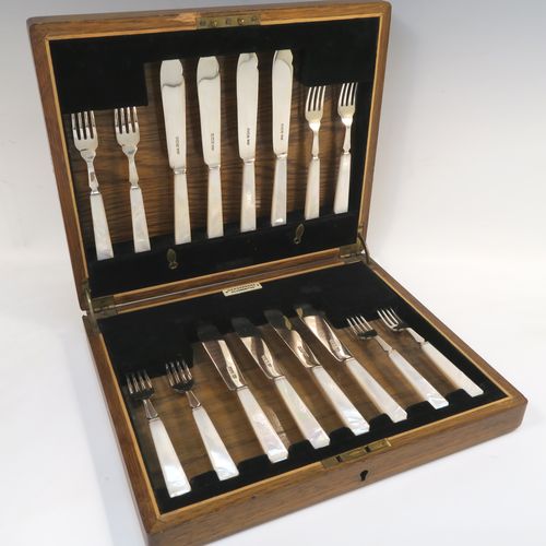 A very elegant Art Deco style Sterling Silver and mother of pearl handled fish eating set for eight people, having plain blades and tines, and with hand-cut mother-of-pearl handles, all fitted into their original black velvet-lined oak presentation box. This stylish Art Deco silver and mother-of-pearl fish set was all made by Wilson and Gill  of Sheffield in 1933. The dimensions of these fine hand-made silver and mother of pearl fish-eaters are length of knife 18 cms (7 inches), and fork 15 cms (6 inches).  
