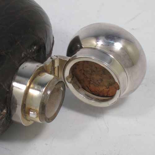 A large and handsome Antique Victorian Sterling Silver and glass whisky flask, with crocodile leather skin mount, and a sight level both sides, having a bayonet fit lid and a pull-off cup with gold-gilt interior. Made in Birmingham in 1900. The dimensions of this fine hand-made antique silver and glass whisky flask are length 18 cms (7 inches), width 9.5 cms (3.75 inches), and depth 4 cms (1.5 inches). Please note slight damage to crocodile skin cover on one side.