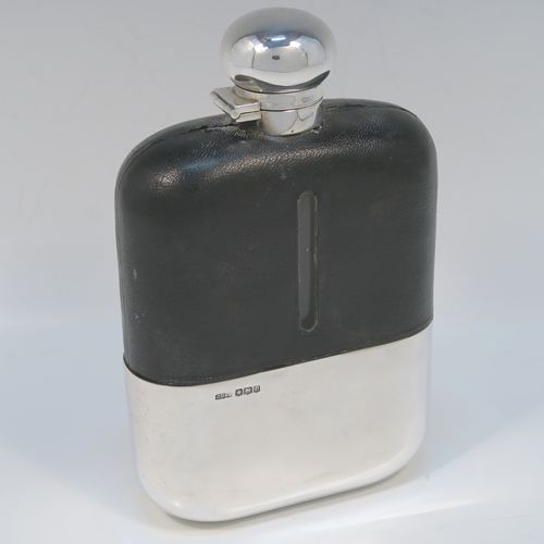 A large and handsome Antique Sterling Silver and glass whisky flask, with dark leather skin mount, and a sight level both sides, having a bayonet fit lid and a pull-off cup with gold-gilt interior. This elegant silver and glass hip flask was made by James Dixon and Sons of Sheffield in 1919. The dimensions of this fine hand-made silver and glass whisky flask are length 19 cms (7.5 inches), width 12 cms (4.75 inches), and depth 4.5 cms (1.75 inches).  