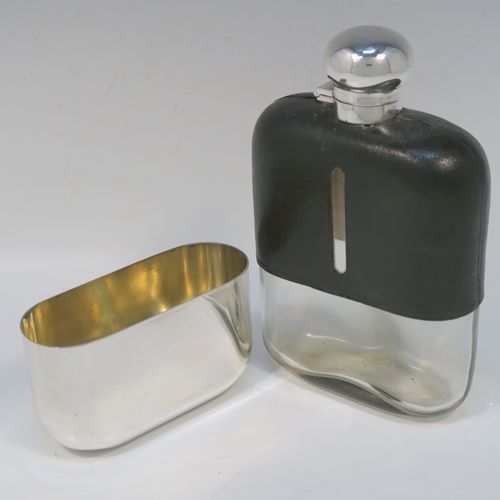 A large and handsome Antique Sterling Silver and glass whisky flask, with dark leather skin mount, and a sight level both sides, having a bayonet fit lid and a pull-off cup with gold-gilt interior. This elegant silver and glass hip flask was made by James Dixon and Sons of Sheffield in 1919. The dimensions of this fine hand-made silver and glass whisky flask are length 19 cms (7.5 inches), width 12 cms (4.75 inches), and depth 4.5 cms (1.75 inches).