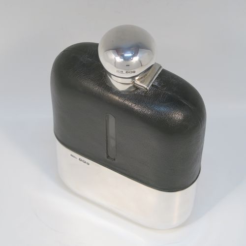A large and handsome Antique Sterling Silver and glass whisky flask, with dark leather skin mount, and a sight level both sides, having a bayonet fit lid and a pull-off cup with gold-gilt interior. This elegant silver and glass hip flask was made by James Dixon and Sons of Sheffield in 1919. The dimensions of this fine hand-made silver and glass whisky flask are length 19 cms (7.5 inches), width 12 cms (4.75 inches), and depth 4.5 cms (1.75 inches).