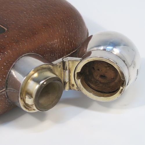 A large and handsome Antique Sterling Silver and glass whisky flask, with leather skin mount, and a sight level both sides, having a bayonet fit lid and a pull-off cup with gold-gilt interior. This elegant silver and glass hip flask was made by James Dixon and Sons of Sheffield in 1924. The dimensions of this fine hand-made silver and glass whisky flask are length 18 cms (7 inches), width 11 cms (4.3 inches), and depth 4 cms (1.5 inches).