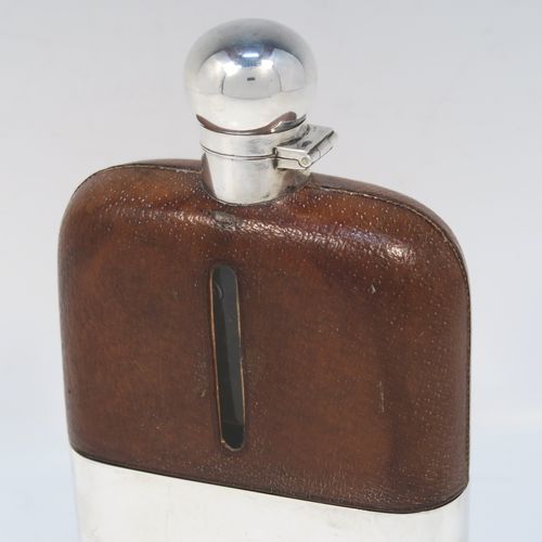 A large and handsome Antique Sterling Silver and glass whisky flask, with leather skin mount, and a sight level both sides, having a bayonet fit lid and a pull-off cup with gold-gilt interior. This elegant silver and glass hip flask was made by James Dixon and Sons of Sheffield in 1924. The dimensions of this fine hand-made silver and glass whisky flask are length 18 cms (7 inches), width 11 cms (4.3 inches), and depth 4 cms (1.5 inches).