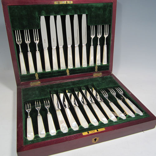 Antique Edwardian sterling silver and mother-of-pearl handled fruit set for twelve people. Having tapering bladed knives with serrated points and three-prong forks, all fitted into an original presentation box with dark green velvet interior. Made by Henry Atkins of Sheffield in 1910. The dimensions of this fine hand-made silver fruit service are length of knife 18 cms (7 inches), and the length of the fork 14.5 cms (5.75 inches). Please note that the brass plaque on top of the box lid is monogrammed.