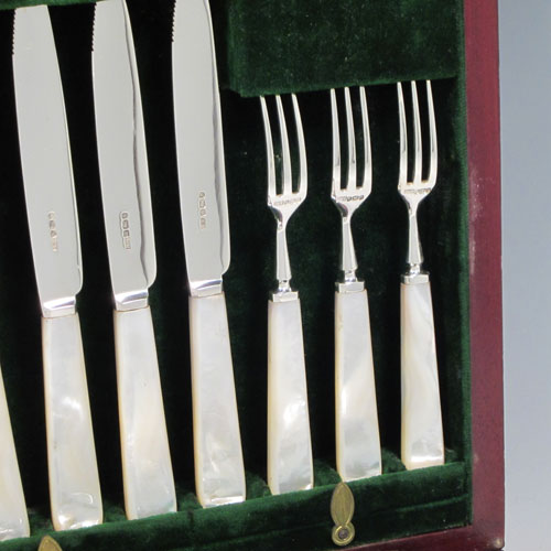 Antique Edwardian sterling silver and mother-of-pearl handled fruit set for twelve people. Having tapering bladed knives with serrated points and three-prong forks, all fitted into an original presentation box with dark green velvet interior. Made by Henry Atkins of Sheffield in 1910. The dimensions of this fine hand-made silver fruit service are length of knife 18 cms (7 inches), and the length of the fork 14.5 cms (5.75 inches). Please note that the brass plaque on top of the box lid is monogrammed.