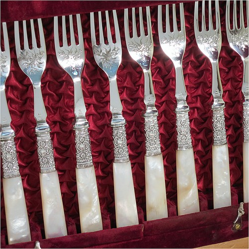 An Antique Victorian silver-plated and mother-of-pearl handled fruit set for twelve people, having hand-engraved tapering bladed knives and four-prong forks with floral decoration, with large hand-chased silver ferrules connecting the mother-of-pearl handles, all fitted into their original maroon satin and velvet-lined presentation box. The ferrules are of hallmarked sterling silver and are made by John Sanderson of Sheffield in 1897. The dimensions of this fine hand-made antique silver fruit service are length of knife 21 cms (8.25 inches), and the length of the fork 17.5 cms (7 inches).