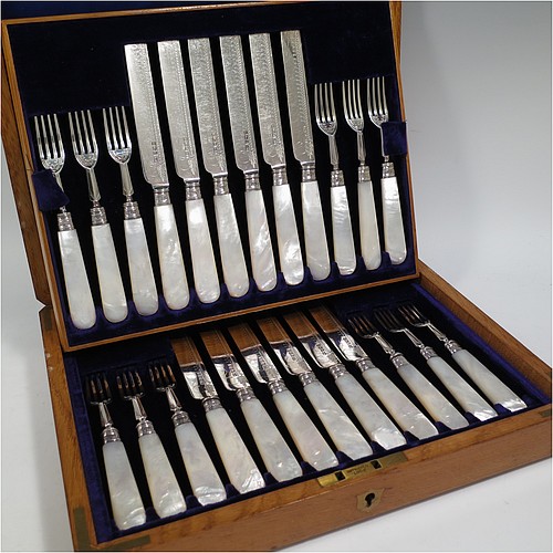 An Antique Edwardian Sterling Silver and mother-of-pearl handled fruit set for twelve people. Having straight-sided rounded-end blade knives, and four-prong forks, with hand-engraved floral decoration, and reed-work ferrules, all fitted into an original presentation box with dark blue velvet interior. Made by George Hancock of Sheffield in 1908. The dimensions of this fine hand-made antique silver fruit service are length of knife 19 cms (7.5 inches), and the length of the fork 15 cms (6 inches).   