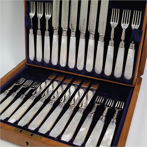 An Antique Edwardian Sterling Silver and mother-of-pearl handled fruit set for twelve people. Having straight-sided rounded-end blade knives, and four-prong forks, with hand-engraved floral decoration, and reed-work ferrules, all fitted into an original presentation box with dark blue velvet interior. Made by George Hancock of Sheffield in 1908. The dimensions of this fine hand-made antique silver fruit service are length of knife 19 cms (7.5 inches), and the length of the fork 15 cms (6 inches).