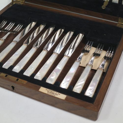 An Antique Edwardian Silver-plated and mother-of-pearl handled fruit set for twelve people. Having straight-sided pointed-end blade knives, and three-prong forks, with hand-engraved reed and diamond decoration, all fitted into an original oak wood presentation box with black velvet-lined interior. Made by Rattray and Co., of Dundee, Scotland, in ca. 1910. The dimensions of this fine hand-made antique silver-plated fruit service are length of knife 16.5 cms (6.5 inches), and the length of the fork 14.5 cms (5.75 inches).