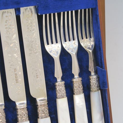 A beautiful Antique Victorian Sterling Silver and mother-of-pearl handled fruit set for 12 people. Having parallel bladed knives and four-prong forks, all hand-engraved with floral decoration, together with ivy-work ferrules connecting the mother-of-pearl handles, and fitted into an original oak canteen with removable top tray and dark blue velvet interior. This very pretty silver and mother-of-pearl fruit eating set was made by Joseph Rogers of Sheffield in 1883. The dimensions of this fine hand-made silver fruit set are length of knife 20 cms (8 inches), length of fork 16.5 cms (6.5 inches).