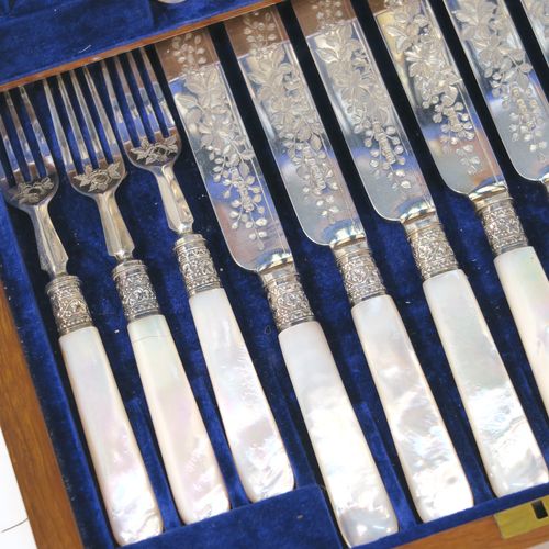 A beautiful Antique Victorian Sterling Silver and mother-of-pearl handled fruit set for 12 people. Having parallel bladed knives and four-prong forks, all hand-engraved with floral decoration, together with ivy-work ferrules connecting the mother-of-pearl handles, and fitted into an original oak canteen with removable top tray and dark blue velvet interior. This very pretty silver and mother-of-pearl fruit eating set was made by Joseph Rogers of Sheffield in 1883. The dimensions of this fine hand-made silver fruit set are length of knife 20 cms (8 inches), length of fork 16.5 cms (6.5 inches).