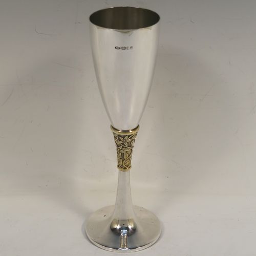A very elegant Sterling Silver champagne flute goblet, having a plain round tapering body, and sitting on a plain round pedestal foot, with an applied central gold-gilt and florally decorated stem. This beautiful silver champagne goblet flute was made by Peter Nicholas and Co. Ltd., of London in 1987. The dimensions of this fine hand-made silver champagne flute are height 21 cms (8.25 inches), diameter at lip 5.5 cms (2.25 inches), and it weighs approx. 175g (5.6 troy ounces).   