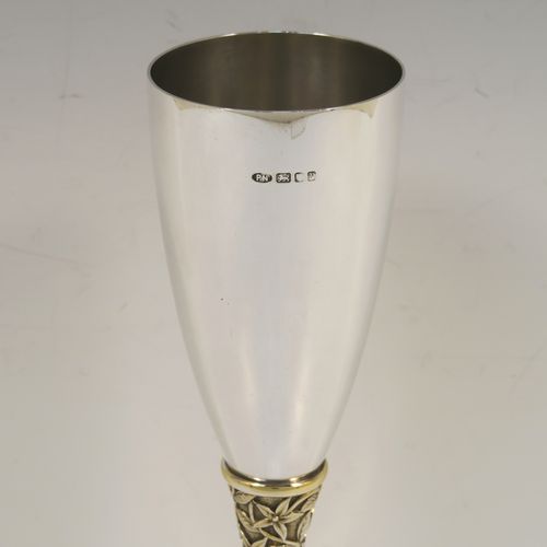 A very elegant Sterling Silver champagne flute goblet, having a plain round tapering body, and sitting on a plain round pedestal foot, with an applied central gold-gilt and florally decorated stem. This beautiful silver champagne goblet flute was made by Peter Nicholas and Co. Ltd., of London in 1987. The dimensions of this fine hand-made silver champagne flute are height 21 cms (8.25 inches), diameter at lip 5.5 cms (2.25 inches), and it weighs approx. 175g (5.6 troy ounces).