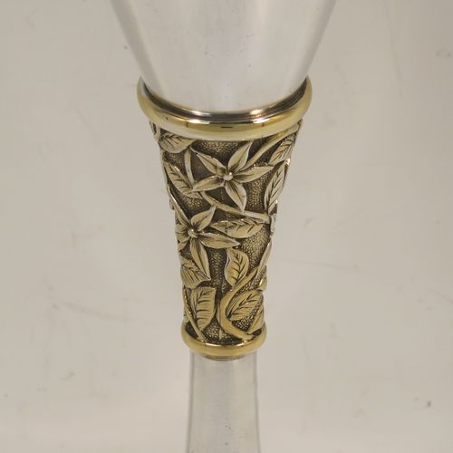 A very elegant Sterling Silver champagne flute goblet, having a plain round tapering body, and sitting on a plain round pedestal foot, with an applied central gold-gilt and florally decorated stem. This beautiful silver champagne goblet flute was made by Peter Nicholas and Co. Ltd., of London in 1987. The dimensions of this fine hand-made silver champagne flute are height 21 cms (8.25 inches), diameter at lip 5.5 cms (2.25 inches), and it weighs approx. 175g (5.6 troy ounces).