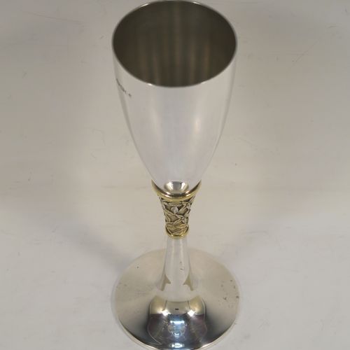 A very elegant Sterling Silver champagne flute goblet, having a plain round tapering body, and sitting on a plain round pedestal foot, with an applied central gold-gilt and florally decorated stem. This beautiful silver champagne goblet flute was made by Peter Nicholas and Co. Ltd., of London in 1987. The dimensions of this fine hand-made silver champagne flute are height 21 cms (8.25 inches), diameter at lip 5.5 cms (2.25 inches), and it weighs approx. 175g (5.6 troy ounces).