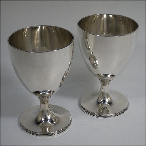 A very handsome pair of Antique Georgian Sterling Silver goblets, having plain round bodies with tapering sides, and sitting on pedestal feet with reeded borders. Made by John Robins of London in 1800. The dimensions of this fine hand-made pair of antique silver goblets are height 12 cms (4.75 inches), diameter at top 8 cms (3 inches), and the total weight is approx. 384g (12.4 troy ounces).   