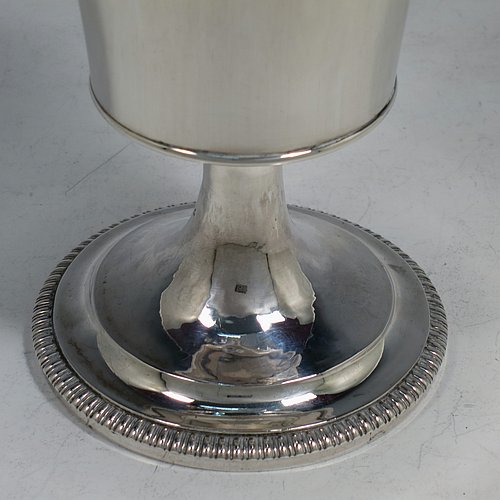 An Antique Georgian Sterling Silver wine goblet, having a plain round tapering body with straight sides, an applied reeded top border, and sitting on a pedestal foot with an applied straight gadroon edge. Made by Henry Nutting & Robert Hennell of London in 1809. The dimensions of this fine hand-made antique silver goblet are height 15 cms (6 inches), diameter at lip 9 cms (3.5 inches), and it weighs approx. 252g (8 troy ounces).