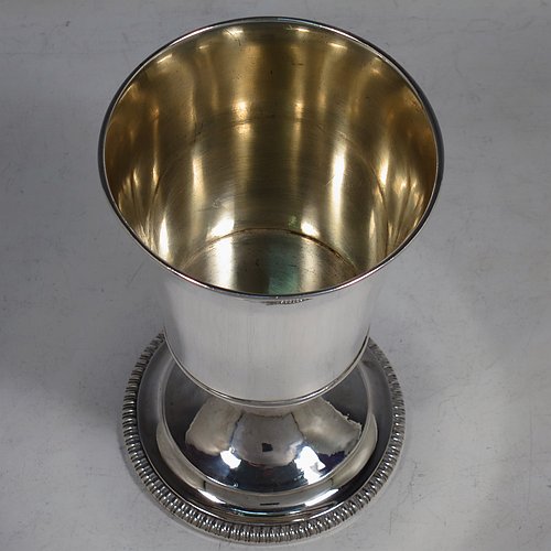 An Antique Georgian Sterling Silver wine goblet, having a plain round tapering body with straight sides, an applied reeded top border, and sitting on a pedestal foot with an applied straight gadroon edge. Made by Henry Nutting & Robert Hennell of London in 1809. The dimensions of this fine hand-made antique silver goblet are height 15 cms (6 inches), diameter at lip 9 cms (3.5 inches), and it weighs approx. 252g (8 troy ounces).