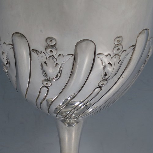 A large Antique Victorian Sterling Silver goblet, having a round tapering body with hand-chased half-fluted swirl and floral decoration, sitting on a pedestal foot, and with a gold-gilt interior. Made by Elkington & co., of Birmingham in 1894. The dimensions of this fine hand-made antique silver goblet are height 21.5 cms (8.5 inches), diameter at lip 10 cms (4 inches), and it weighs approx. 242g (7.8 troy ounces).