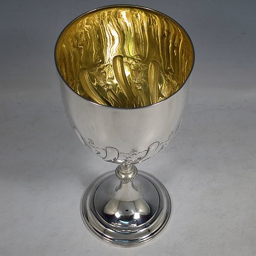A large Antique Victorian Sterling Silver goblet, having a round tapering body with hand-chased half-fluted swirl and floral decoration, sitting on a pedestal foot, and with a gold-gilt interior. Made by Elkington & co., of Birmingham in 1894. The dimensions of this fine hand-made antique silver goblet are height 21.5 cms (8.5 inches), diameter at lip 10 cms (4 inches), and it weighs approx. 242g (7.8 troy ounces).