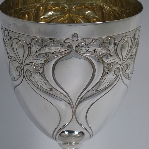 A large Antique Edwardian Sterling Silver Art Nouveau style goblet, having a round tapering body with hand-chased anthemion leaf work and plain tear-drop shaped cartouches, sitting on a pedestal foot with a bead border, and with a gold-gilt interior. Made by the Cooper Brothers of Sheffield in 1904. The dimensions of this fine hand-made antique silver Art Nouveau goblet are height 20 cms (8 inches), diameter at lip 10 cms (4 inches), and it weighs approx. 285g (9.2 troy ounces).