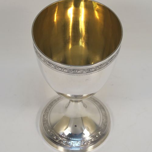 A very pretty Antique Georgian Sterling Silver goblet, having a round tapering body with a top band of hand-engraved floral and scroll decoration, sitting on a pedestal foot with a reeded border and matching engraving, and with a gold-gilt interior. This beautiful antique silver goblet was made John Emes of London in 1804. The dimensions of this fine hand-made antique silver goblet are height 14 cms (5.5 inches), diameter at lip 8 cms (3 inches), and it weighs approx. 158g (5 troy ounces).   