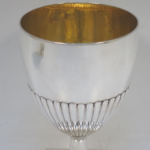 A very fine and handsome Antique Georgian Sterling Silver pair of goblets, having round bodies with hand-chased half-fluted decoration, gold-gilt interiors, and sitting on pedestal feet with square bases. Made by John Wakelin and Robert Garrard of London in 1796. The dimensions of this fine hand-made pair of antique silver goblets are height 15 cms (6 inches), diameter at top 9.5 cms (3.75 inches), and their total weight is approx. 509g (16.5 troy ounces).