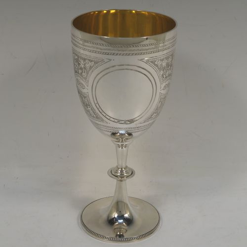 A large and very pretty Antique Victorian Sterling Silver goblet, having a round tapering body with hand-engraved floral and scroll decoration surrounding two round vacant cartouches on either side, sitting on a pedestal foot with applied bead-edged borders, and with a gold-gilt interior. This beautiful antique silver wine goblet was made by Charles Stuart Harris of London in 1887. The dimensions of this fine hand-made antique silver goblet are height 18.5 cms (7.25 inches), diameter at lip 8.5 cms (3.3 inches), and it weighs approx. 224g (7.2 troy ounces).