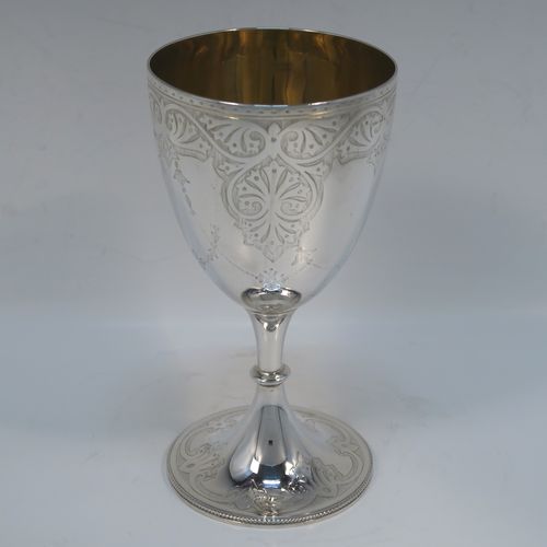 A very pretty Antique Victorian Sterling Silver goblet, having a round body with tapering sides and hand-engraved floral and scroll decoration, a gold-gilt interior, and sitting on a pedestal foot with hand-engraved decoration and an applied bead-edged border. This beautiful silver goblet was made by Joseph Rogers of Sheffield in 1875. The dimensions of this fine hand-made antique silver goblet are height 17 cms (6.6 inches), diameter at lip 9 cms (3.5 inches), and it weighs approx. 211g (6.8 troy ounces).  