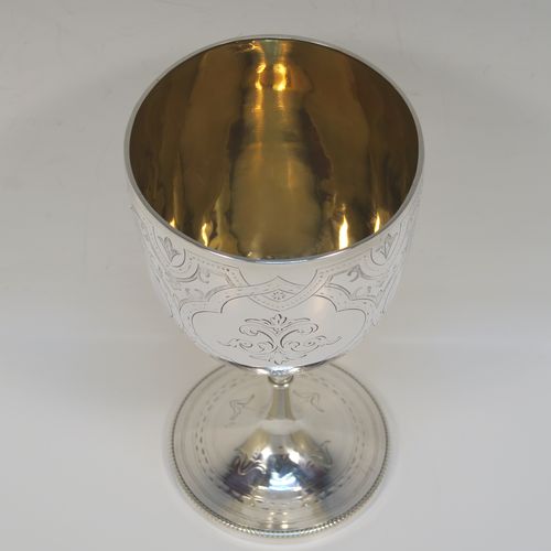 A pretty Antique Victorian Sterling Silver goblet, having a round bellied body with hand-engraved floral and scroll decoration, a gold-gilt interior, and sitting on a pedestal foot with hand-engraved decoration and an applied bead-edged border. This beautiful silver goblet was made by Henry Holland of London in 1870. The dimensions of this fine hand-made antique silver goblet are height 16.5 cms (6.5 inches), diameter at lip 8.5 cms (3.3 inches), and it weighs approx. 188g (6 troy ounces).