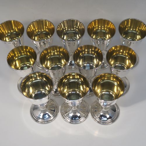 A very handsome set of twelve Sterling Silver  goblets, having plain round tapering bodies with gold-gilt interiors, sitting on round baluster stems  and plain pedestal feet with reeded borders. This beautiful set of silver goblets were all made by J. B. Chatterley of Birmingham in 1977. The dimensions of these fine hand-made set of silver goblets are height 12.5 cms (5 inches), diameter at lip 6.5 cms (2.5 inches), and they weigh a total of approx. 980g (62 troy ounces).   