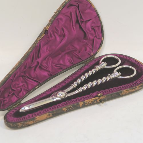 A very pretty Antique Victorian Sterling Silver pair of grape shears or scissors, with cast handles in a twisted style, with plain loop handles and hand-chased terminals, all in its original maroon velvet and stain-lined presentation box. This beautiful pair of antique silver grape scissors were made by Edward Hutton  of London in 1889. The dimensions of this fine hand-made pair of antique silver grape shears are length 17.5 cms (7 inches), and they weigh approx. 109g (3.5 troy ounces).  