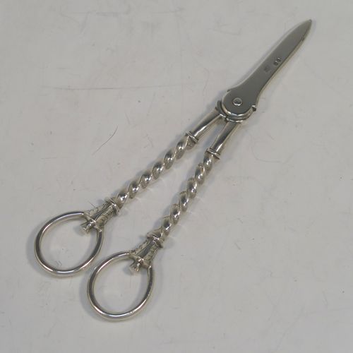 A very pretty Antique Victorian Sterling Silver pair of grape shears or scissors, with cast handles in a twisted style, with plain loop handles and hand-chased terminals, all in its original maroon velvet and stain-lined presentation box. This beautiful pair of antique silver grape scissors were made by Edward Hutton of London in 1889. The dimensions of this fine hand-made pair of antique silver grape shears are length 17.5 cms (7 inches), and they weigh approx. 109g (3.5 troy ounces).