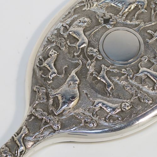A beautiful Antique Victorian Indian Sterling Silver hand-mirror, having an oval body with a hand-chased scene of animals including lions, deer, dogs, leopards, and elephants, surrounding a central vacant round cartouche, and an oval mounted mirror in a plain frame. This fantastic silver hand mirror was probably made for the Indian market in ca. 1880. The dimensions of this fine hand-made silver hand mirror are length 28 cms (11 inches), and width of main body 11 cms (4.3 inches).