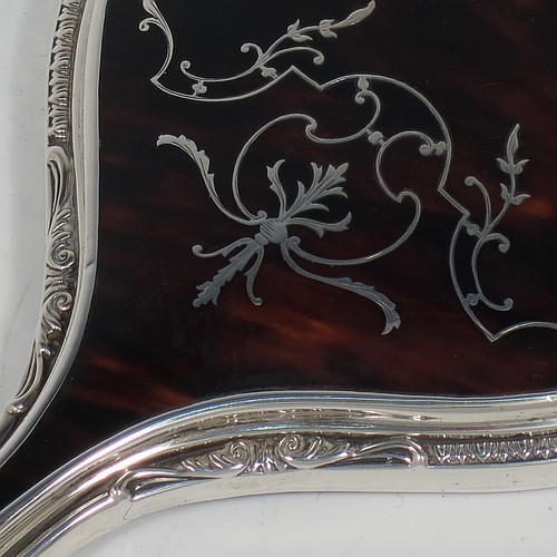 A Sterling Silver and Tortoise-shell hand-mirror, having an oval body with an applied floral border, with very pretty Neoclassical style inlaid tortoiseshell decoration, and an original bevelled mirror. Made by Mappin and Webb of Birmingham in 1928. The dimensions of this fine hand-made silver and tortoise-shell hand mirror are length 28 cms (11 inches), and width of mirror 11 cms (4.25 inches).