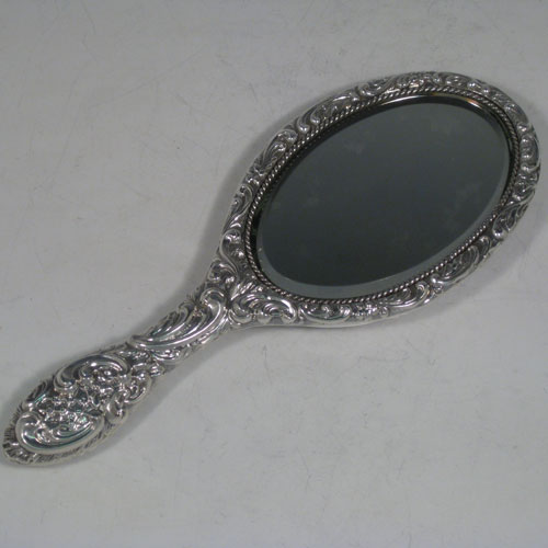 Antique Victorian sterling silver hand-mirror, having an oval body with hand-chased floral decoration and cherub, a central vacant cartouche, and an oval bevelled mirror with rope-twist border. Made by Henry Hayes of Birmingham in 1898. The dimensions of this fine hand-made silver hand mirror are length 26 cms (10 inches), and width 10 cms (4 inches). Please note that the mirror surface shows signs of very slight clouding.