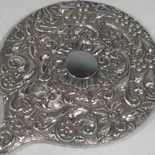Antique Edwardian sterling silver hand-mirror, having a round body with hand-chased floral decoration, a central vacant cartouche, and a round bevelled mirror. Made by Nathan and Hayes of Chester in 1902. The dimensions of this fine hand-made silver hand mirror are length 28 cms (11 inches), and width 16.5 cms (6.5 inches).