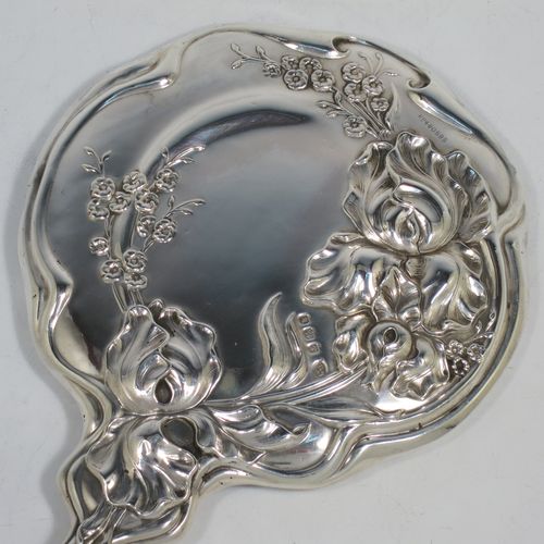 A very pretty Art Nouveau Antique Edwardian Sterling Silver hand-mirror, having a round body with hand-chased Iris floral decoration, and a round bevelled mirror with a lobed border. Made by William Aitken of Birmingham in 1909. The dimensions of this fine hand-made antique Art Nouveau silver hand mirror are length 28 cms (11 inches), and diameter 16 cms (6.25 inches).
