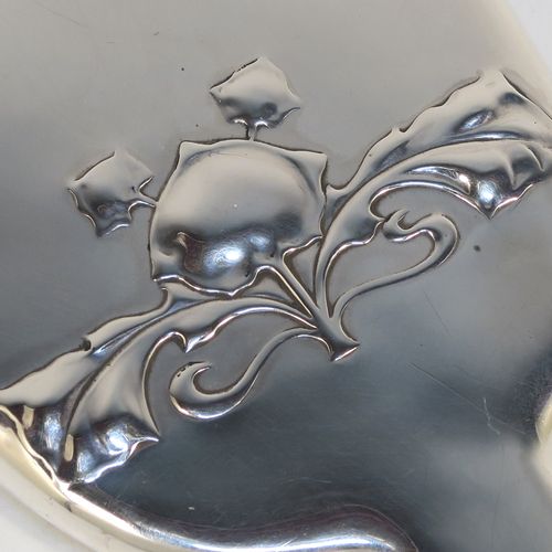 A very pretty and rare Antique Edwardian Arts and Crafts style Sterling Silver hand-mirror, having a plain rounded rectangular body with a hand-chased floral style motif in the Cymric pattern, an original bevelled mirror, and a plain handle. Designed and made by the famous Liberty and Company of Birmingham in 1902. The dimensions of this fine hand-made Arts and Crafts style silver hand mirror are length 24 cms (9.5 inches), and width 9 cms (3.5 inches).